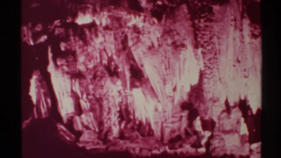 At the end of the clip, silhouetted men remain near the base of the New Mexico cave wall under strong red illumination.