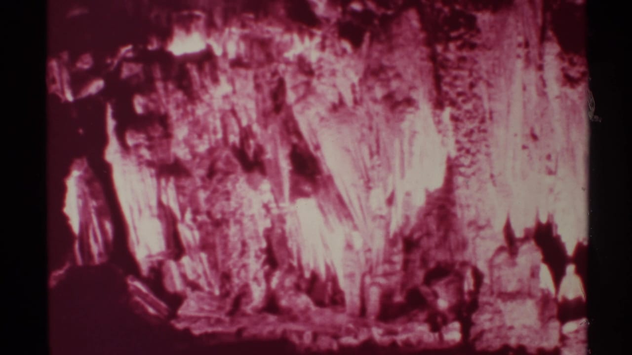 1972 8mm New Mexico cave footage showing dark visitor silhouettes beneath bright magenta-tinted mineral formations.
