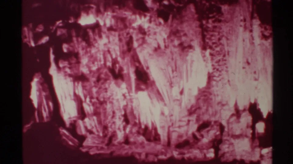 1972 home-movie view of visitors in a New Mexico cave, with stalactite-like formations and heavy reddish film color shift.