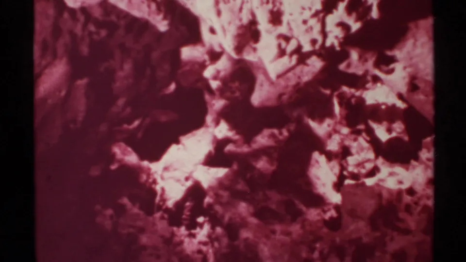 Magenta-tinted 8mm close view of rugged New Mexico cave rock textures and shadowed mineral formations.