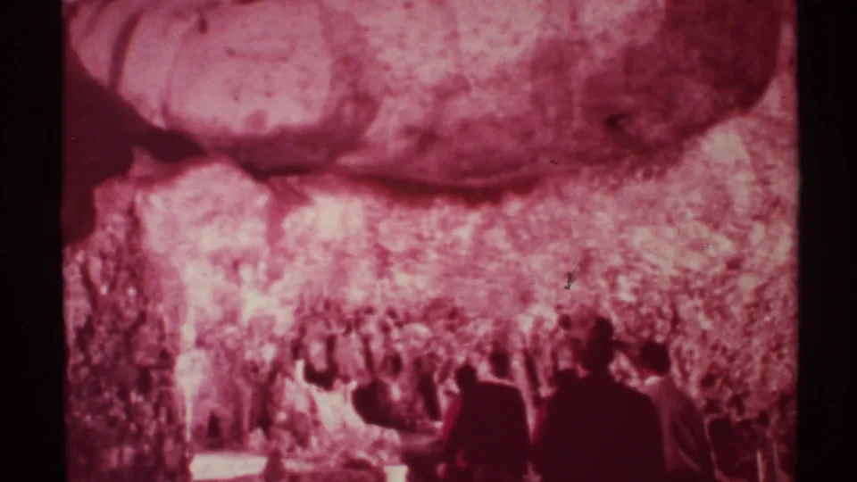 1972 New Mexico 8mm frame showing adults in formal attire entering or standing inside a cave passage.