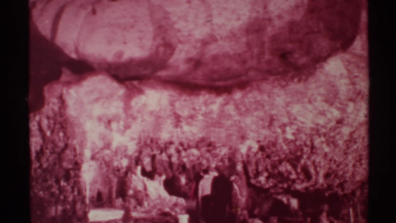 1972 New Mexico 8mm frame showing hikers as dark silhouettes beneath a magenta-shifted rocky canyon wall.