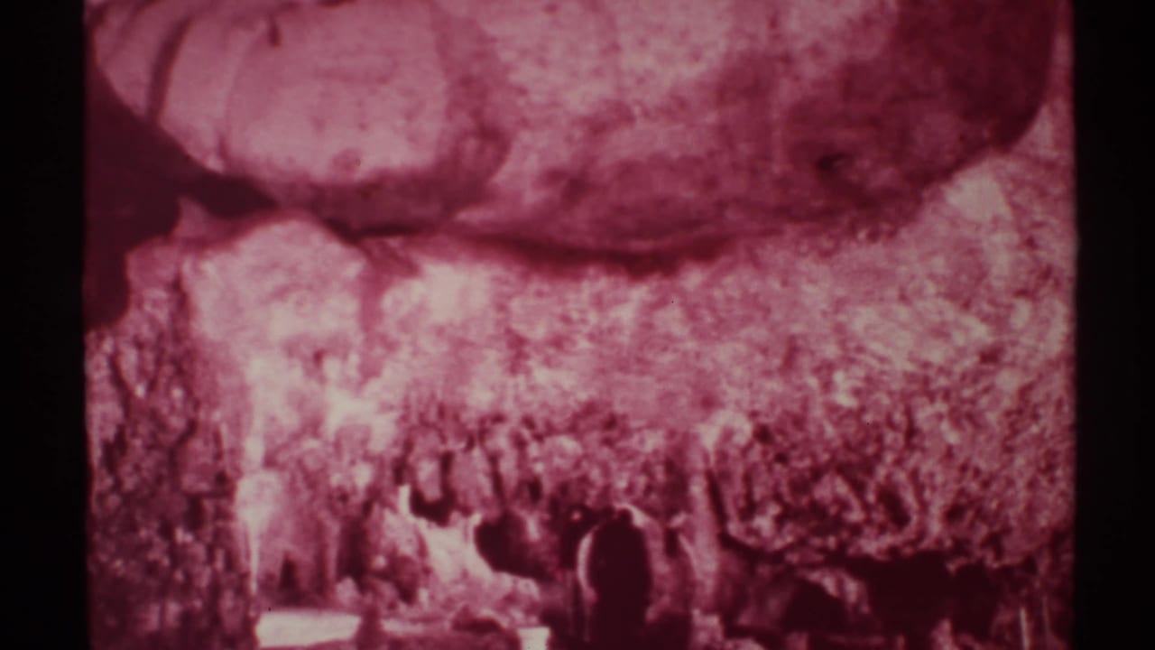 Rocky canyon wall with hikers silhouetted along the bottom of the frame.