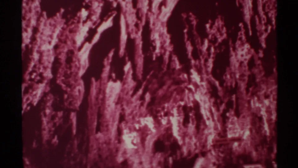 1972 New Mexico 8mm frame focused on shadowy cave formations and bright rock highlights inside the passage.