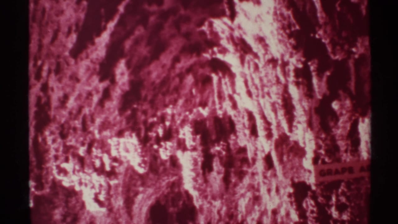1972 8mm New Mexico cave interior view with rough rock formations, bright highlights, and a strong magenta film cast.