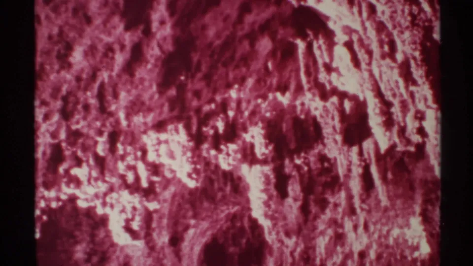 Soft, grainy 1972 8mm view of a New Mexico cave formation, dominated by magenta color and bright rock highlights.