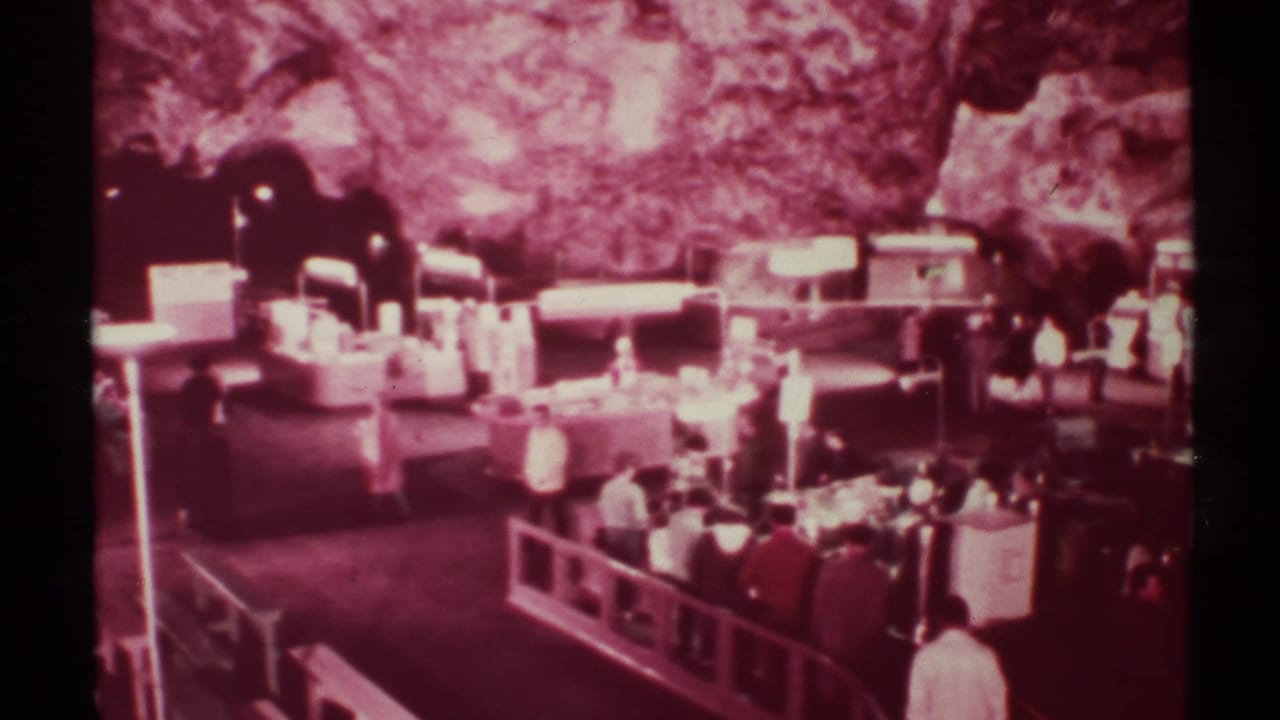 Visitors stand and walk beside railings under a rocky cave ceiling with display counters nearby.