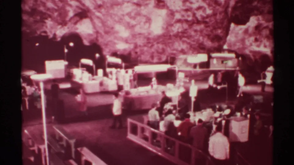 Wide 1972 New Mexico cave-market view with one visitor crossing the floor and others gathered by rails and counters.