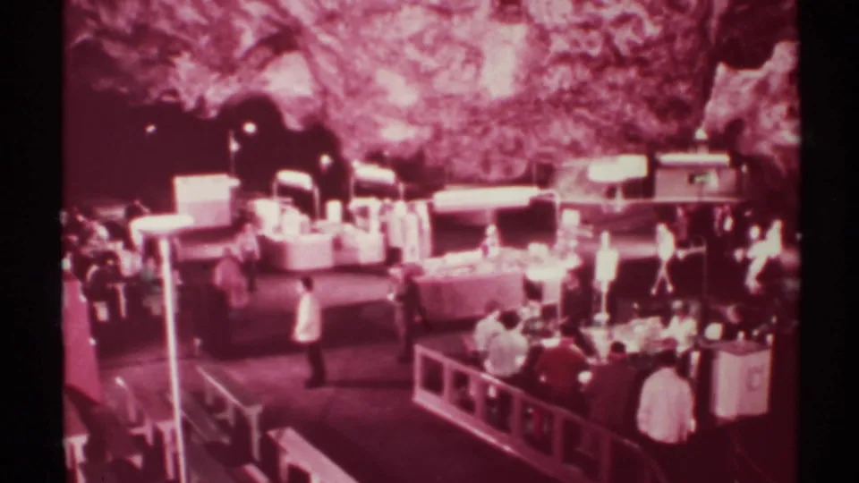 Wide 1972 New Mexico cave market frame with visitors behind rails, display counters, and a white-shirted figure near the foreground.