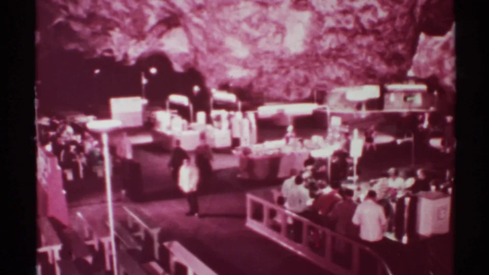 Home-movie view of visitors walking through a New Mexico cavern market, tinted magenta by aged 8mm film.