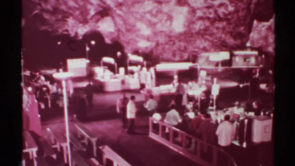 1972 8mm New Mexico home-movie frame showing visitors near vendor counters beneath rough stone walls in a cave-like interior.