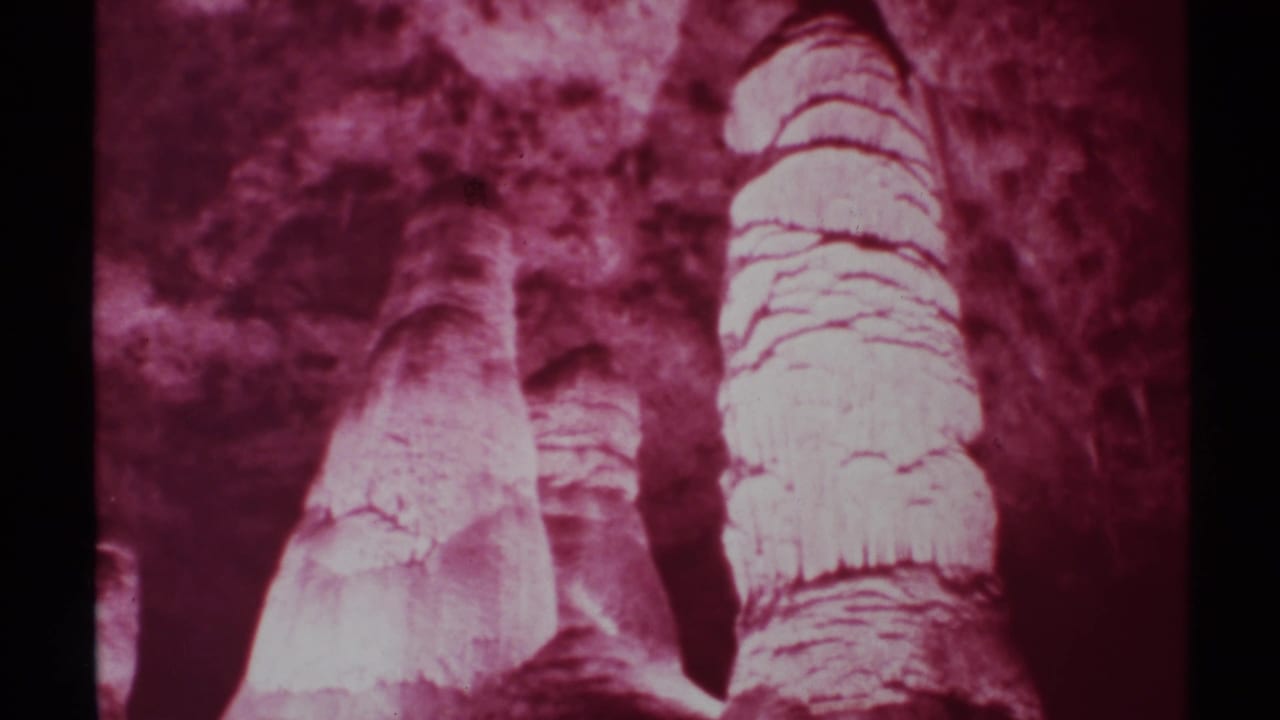 Tall cave formations with layered surfaces under magenta-tinted film color.