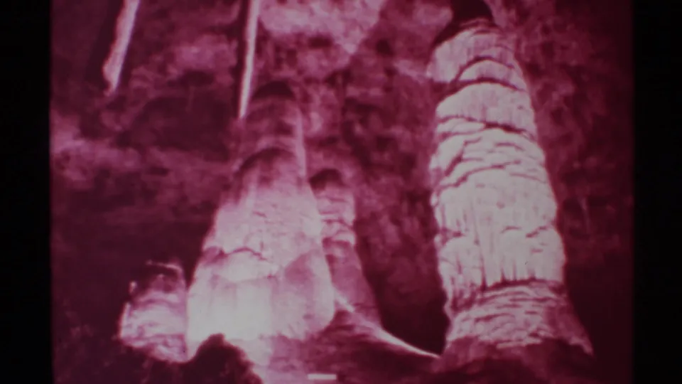 1972 New Mexico cave frame showing layered formations, darker wall openings, and visible 8mm color shift and grain.