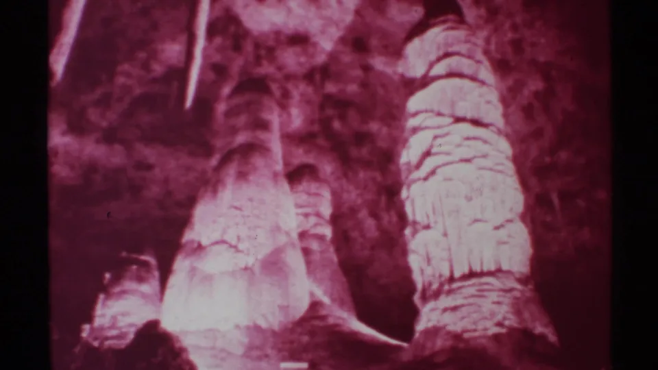 New Mexico cave footage from 1972 shows bright red-lit mineral columns against darker cave walls in a home-movie frame.