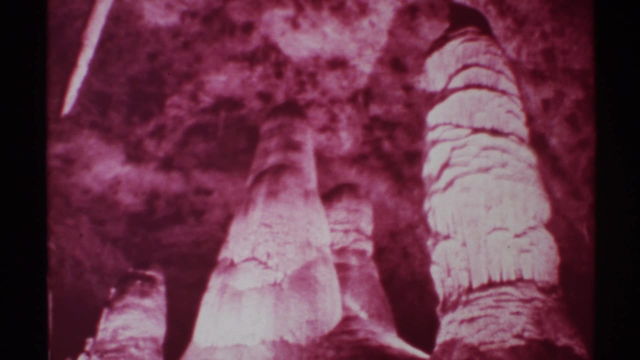 1972 New Mexico 8mm frame looking upward at tall cave formations with reflected highlights and a strong magenta-purple cast.