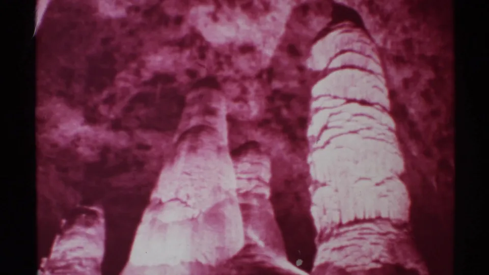 1972 New Mexico 8mm view of pale cave formations rising toward a rough ceiling, separated by a dark vertical gap.