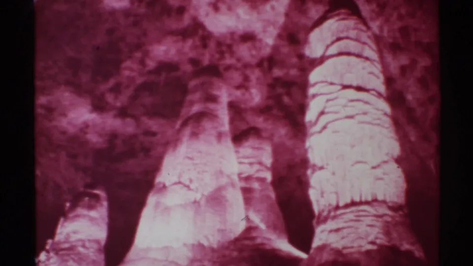 1972 New Mexico home-movie frame showing an upward cave perspective with layered rock texture and heavy magenta color shift.