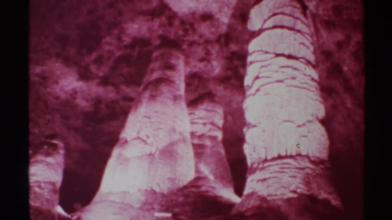 1972 8mm frame showing magenta-tinted cave stalagmites and textured rock surfaces, supported by the supplied New Mexico metadata.
