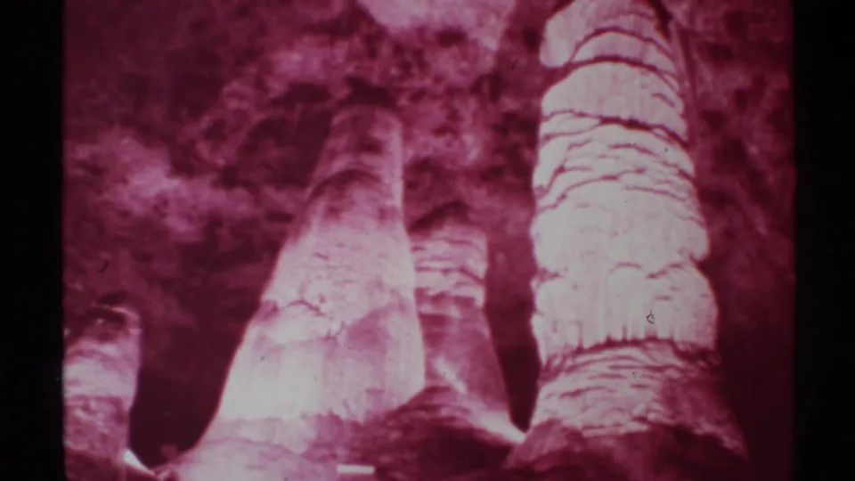 1972 8mm frame showing magenta-tinted cave stalagmites and textured rock surfaces, supported by the supplied New Mexico metadata.