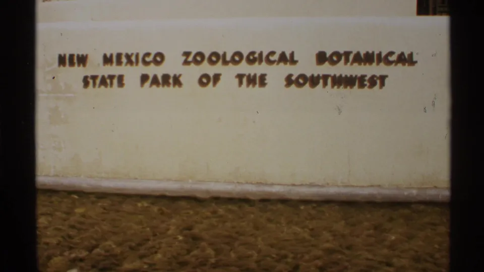 1972 8mm frame showing raised brown lettering on a cream wall for the New Mexico Zoological Botanical State Park of the Southwest.