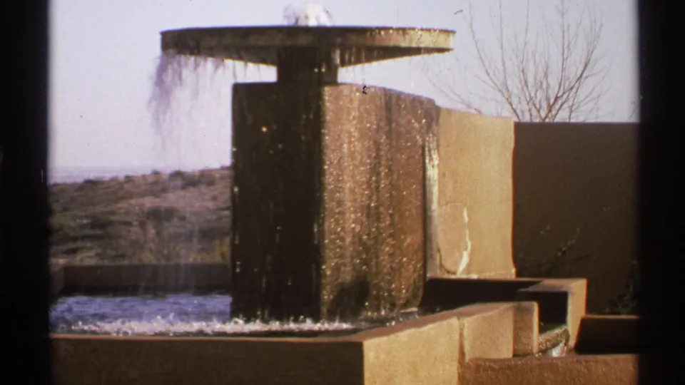 1972 New Mexico 8mm still of a modernist fountain with cascading water and desert-toned concrete forms.