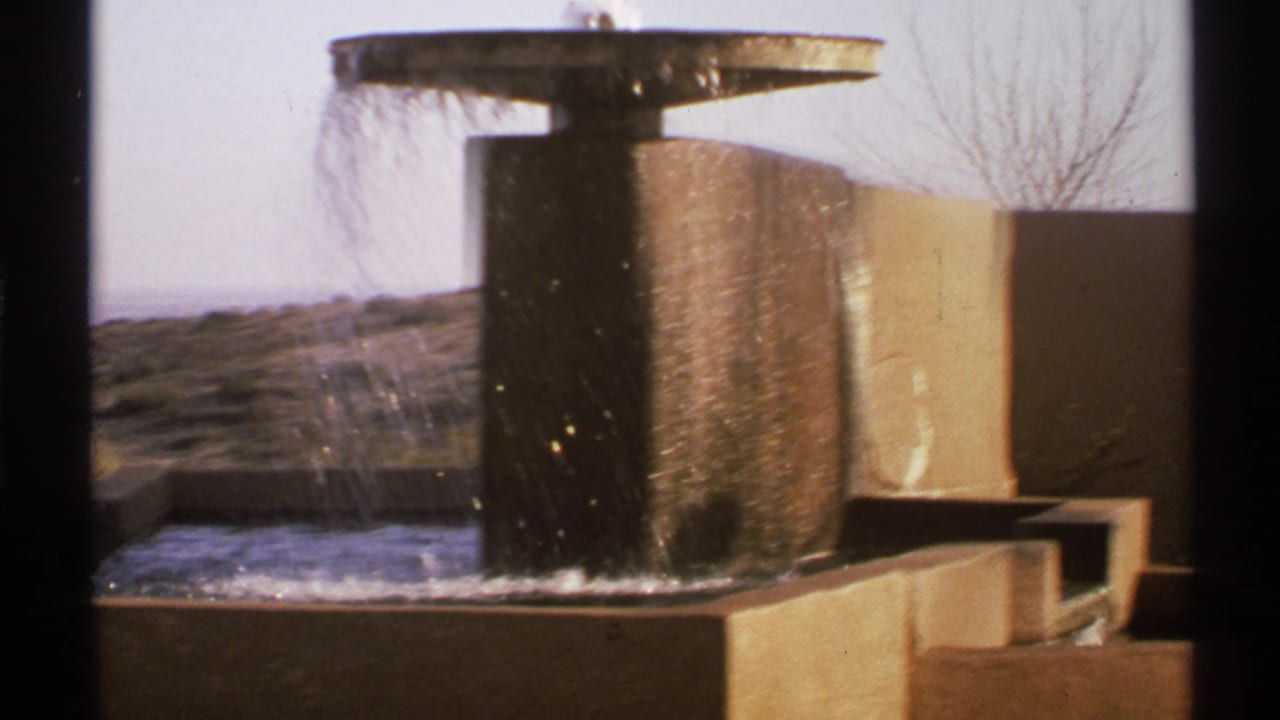 Modernist outdoor fountain with water falling over a dark central form.