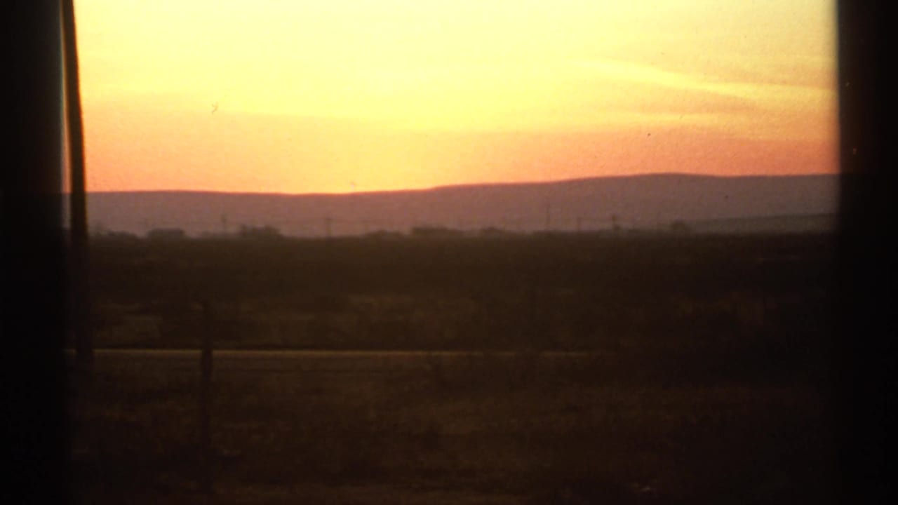 Bright sunrise sky above a dark rural horizon and silhouetted foreground.