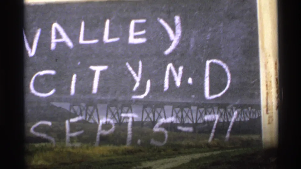 Transition frame where the Valley City title card overlaps a view of a long railway trestle in North Dakota.