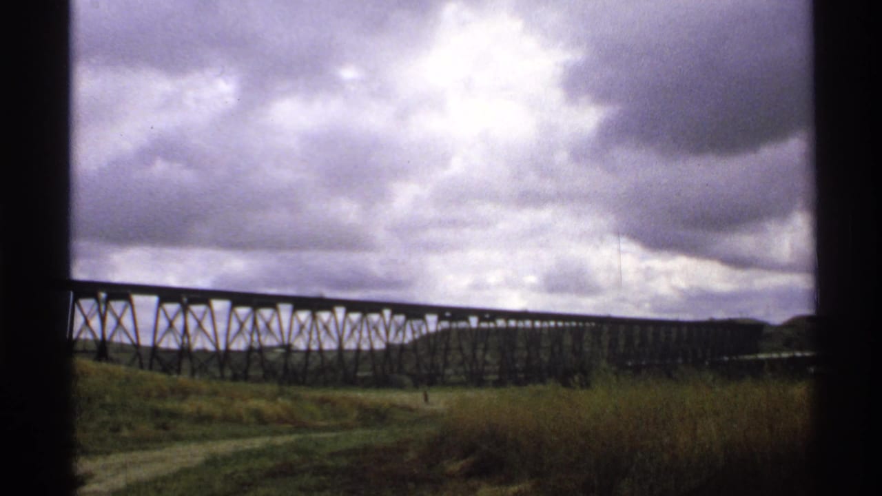 North Dakota home-movie view of the trestle bridge continuing across the grassy landscape under dense cloud cover.