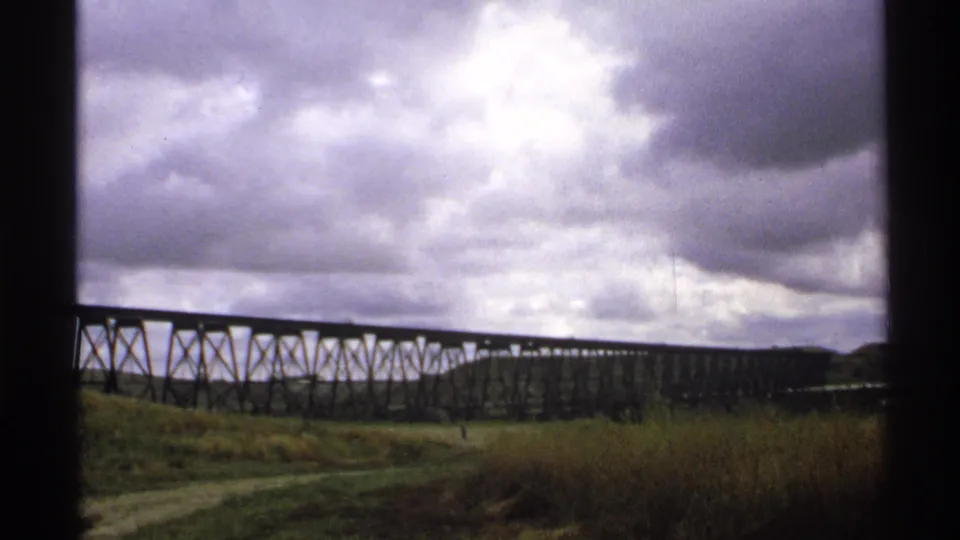 North Dakota home-movie view of the trestle bridge continuing across the grassy landscape under dense cloud cover.
