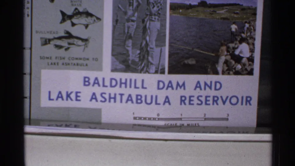 1972 North Dakota 8mm frame of the Baldhill Dam and Lake Ashtabula Reservoir sign with printed fishing imagery.