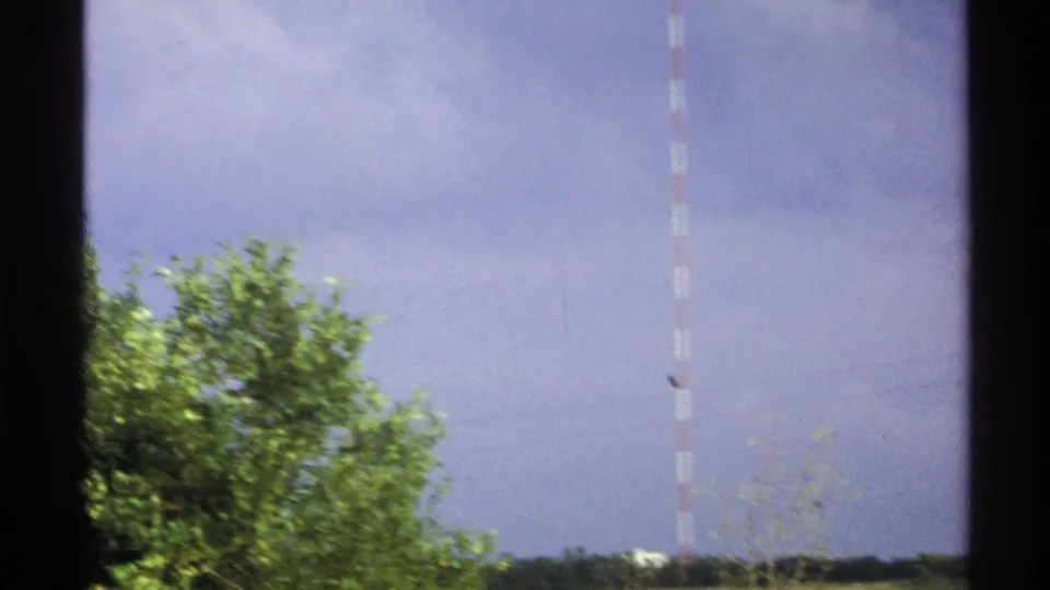Wide 1972 North Dakota landscape view with the KTHI-TV Tower visible beyond green trees, open fields, and a cloudy sky.