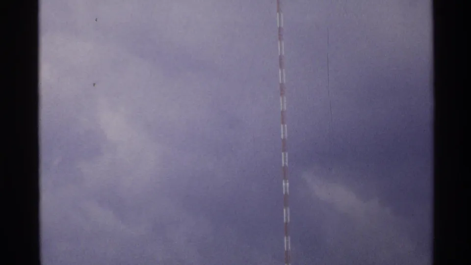 Final 1972 8mm frame holds the red-and-white mast near the right edge, with soft cloud forms and film texture visible.