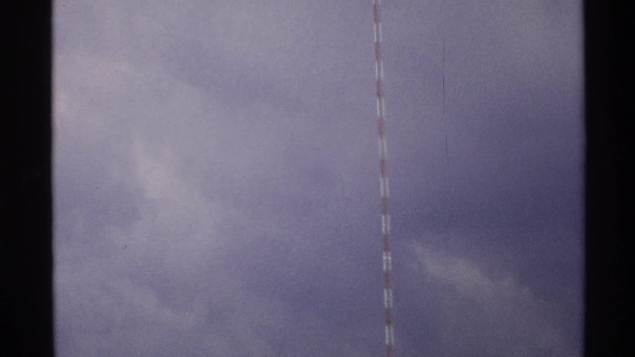 1972 North Dakota 8mm frame showing part of a red-and-white striped tower against a purplish overcast sky.