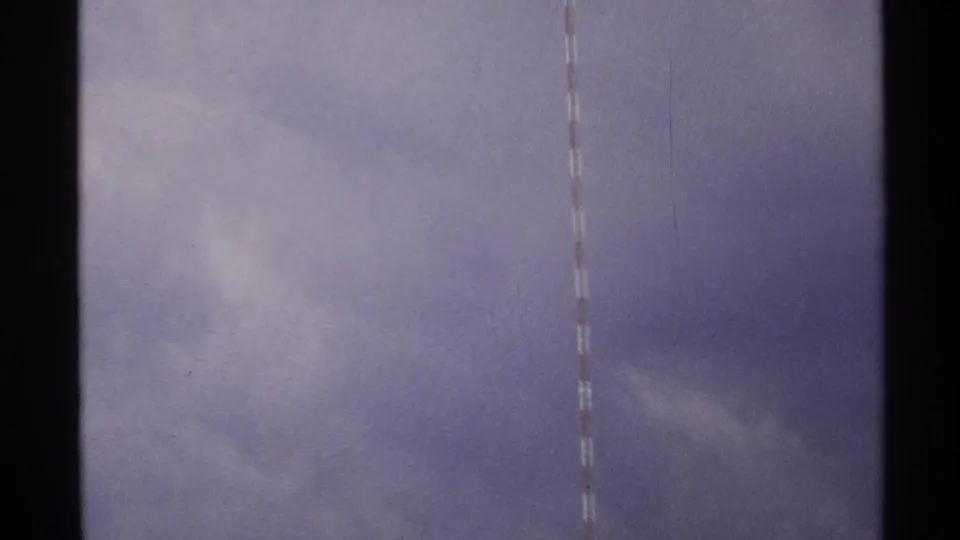 1972 North Dakota 8mm frame showing part of a red-and-white striped tower against a purplish overcast sky.