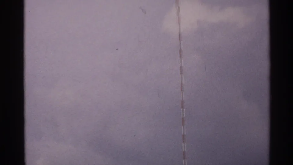 1972 North Dakota 8mm frame with a faint red-and-white tower segment and cloudy purple-gray sky.