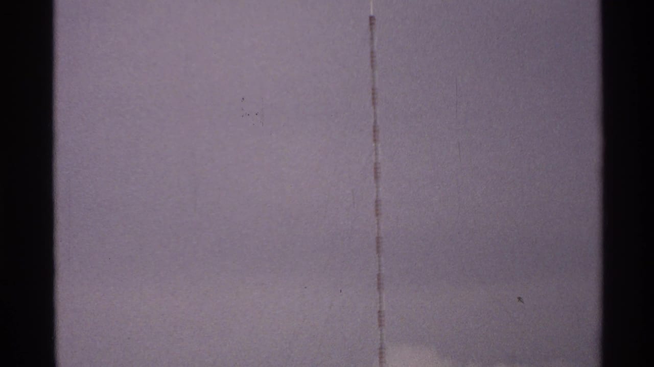 Dark vertical tower forms and thin lines against a pale sky.