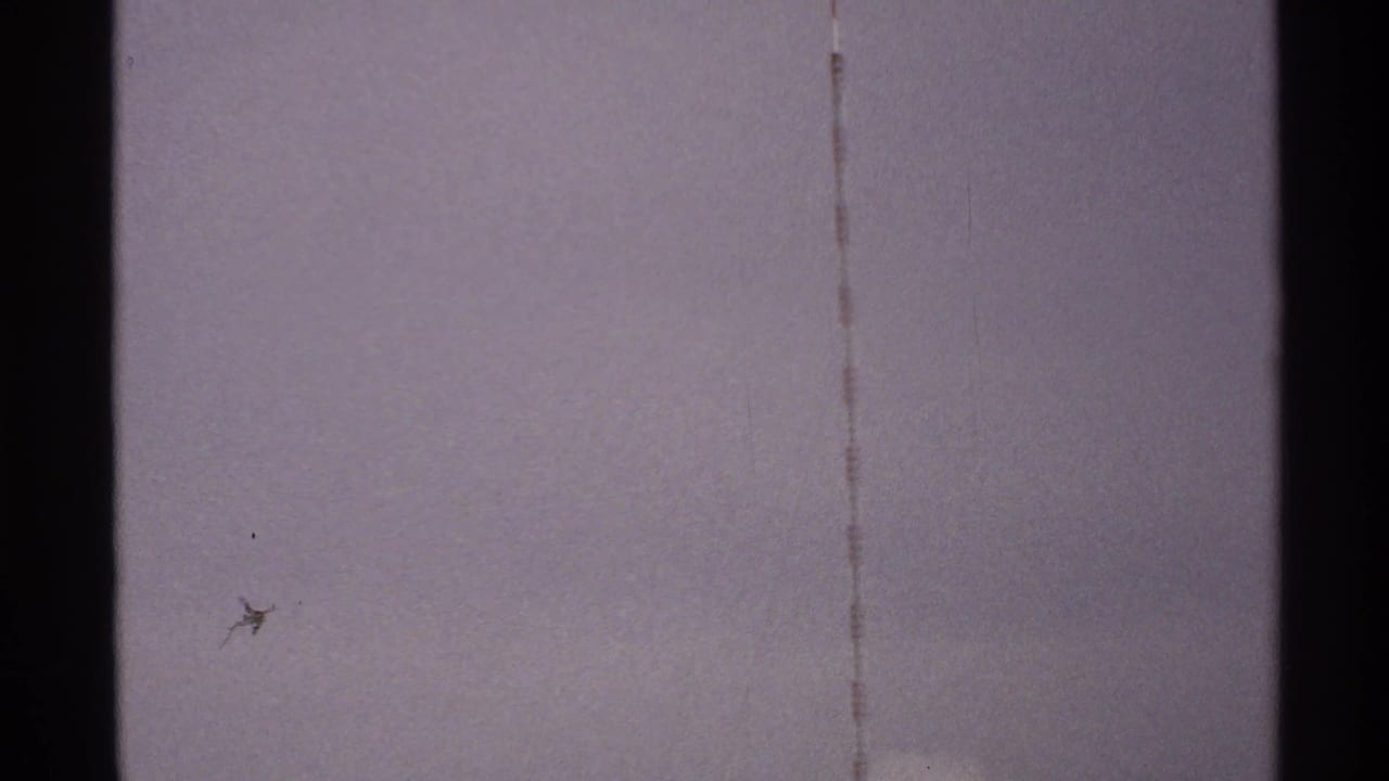 A central dark tower or antenna element crosses a pale 1972 North Dakota sky, with faint lines and visible 8mm grain.