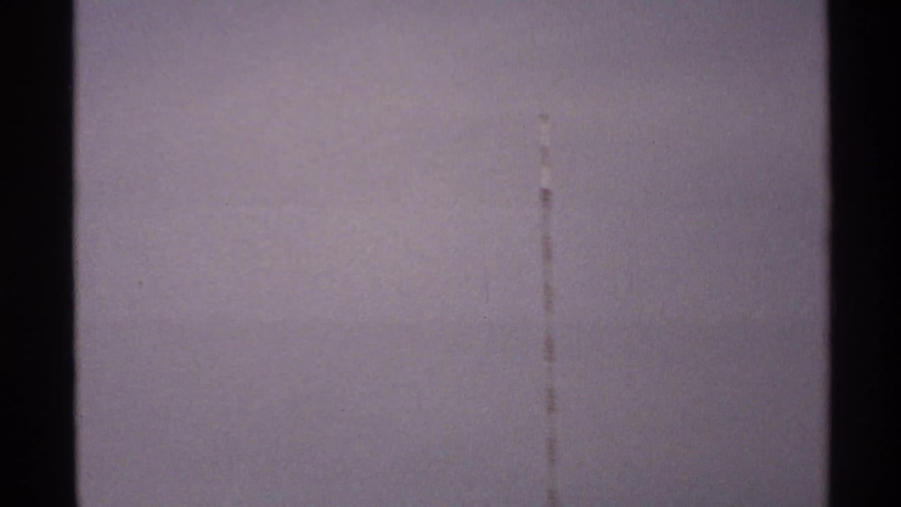 Muted sky with a vertical scratch and darker cloud band at the bottom.