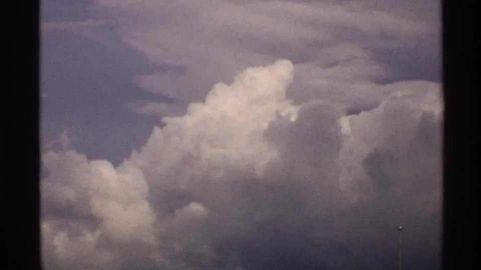 1972 North Dakota 8mm frame with a bright cumulus formation rising from darker cloud cover in a stormy sky.