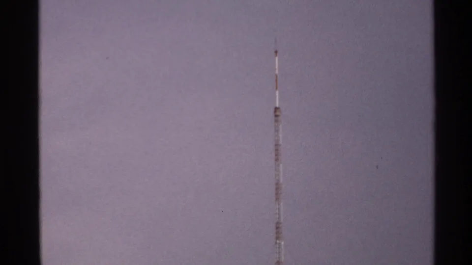 A slender red-and-white communication tower stands high against the hazy North Dakota sky in 1972 home-movie footage.