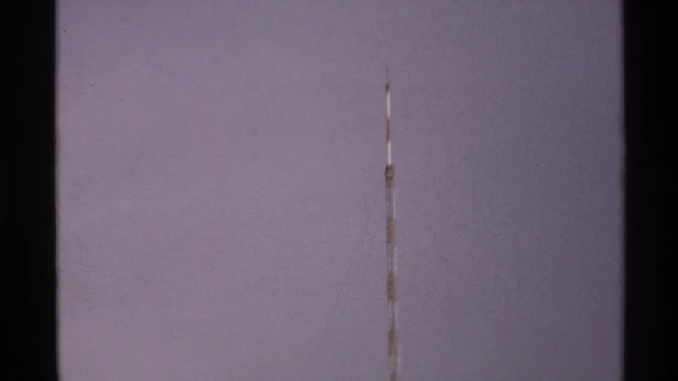 The 8mm frame holds on the lower visible span of a red-and-white tower against a muted North Dakota sky.