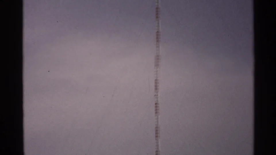 1972 North Dakota 8mm frame showing a faint vertical antenna against a pale sky with visible film-edge bars and grain.