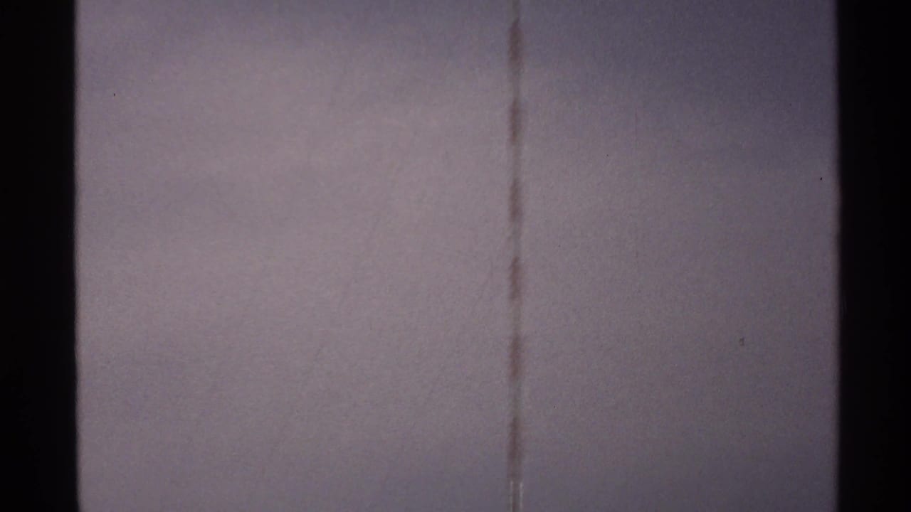 North Dakota 1972 home-movie frame with the antenna faintly visible against a washed, grainy sky.