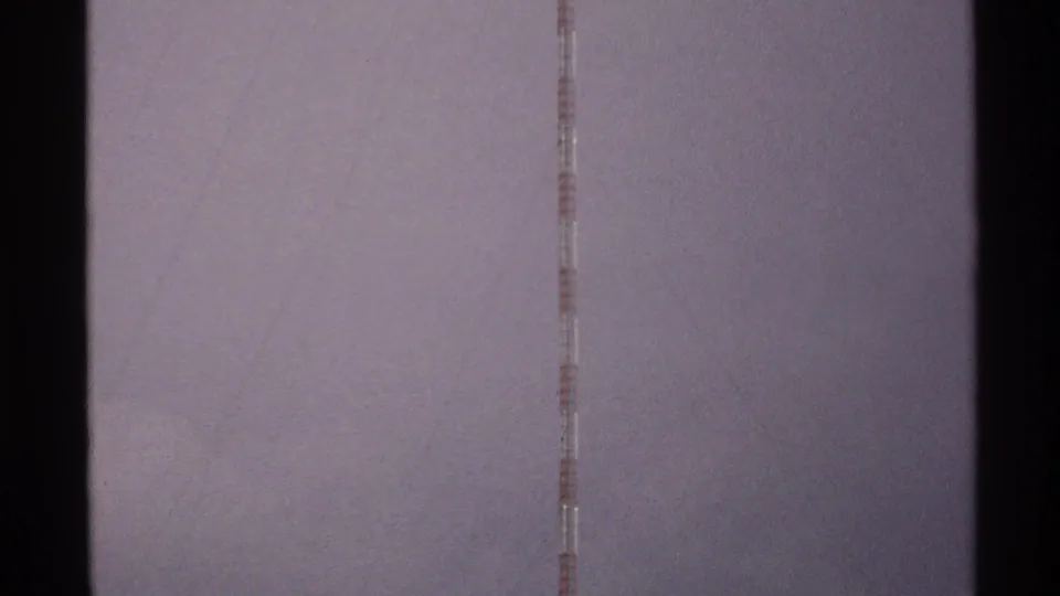 8mm frame from 1972 North Dakota showing a vertical antenna segment through a faded, scratched sky field.