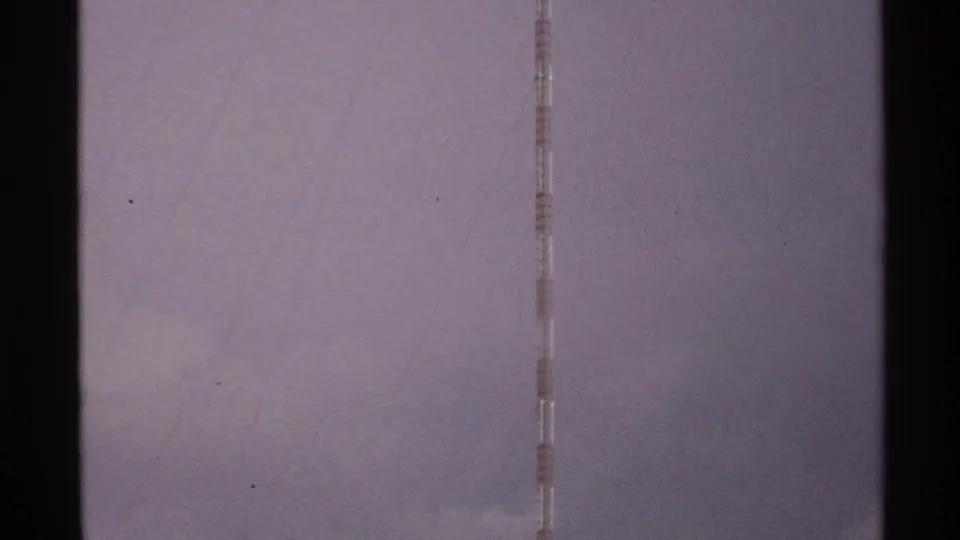 A tall red and white striped tower rises into a cloudy North Dakota sky in 1972 8mm home-movie footage.