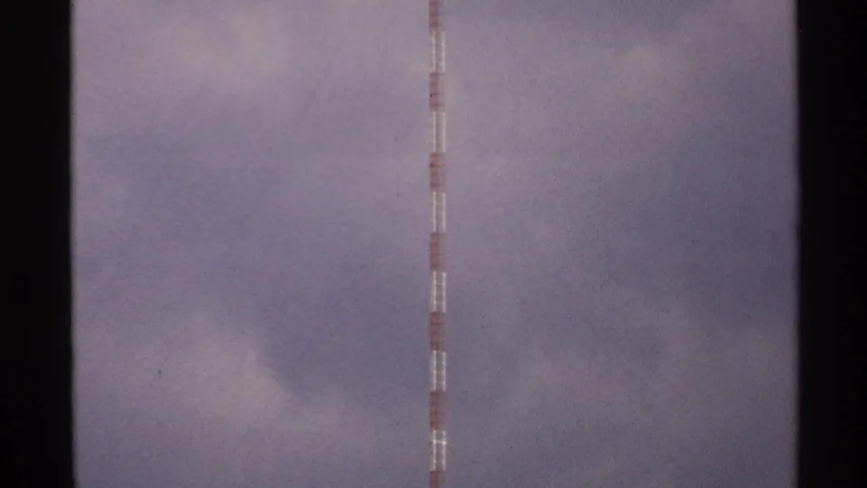 The camera holds on the upper section of a red and white tower against soft clouds in 1972 North Dakota footage.