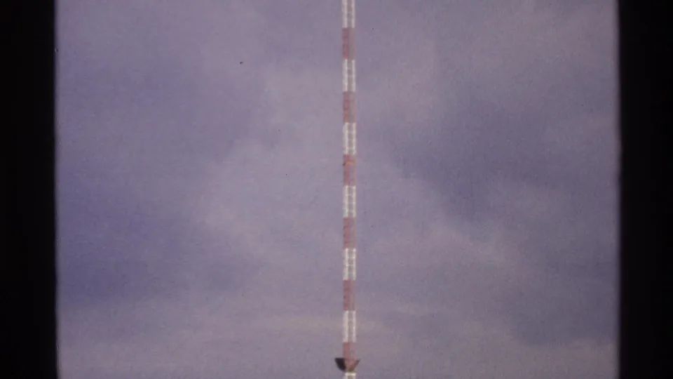 The striped tower extends down toward a small dark structural detail, surrounded by cloudy North Dakota sky.