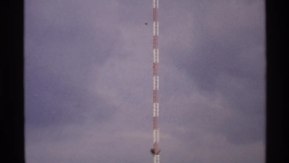 1972 North Dakota 8mm frame showing a striped communications tower against a cloudy sky, with film gate edges visible.