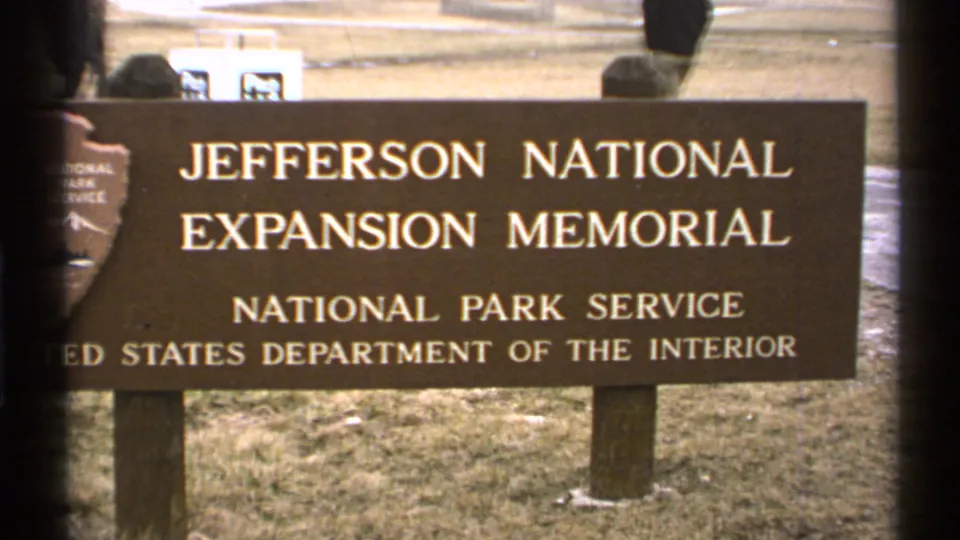 1972 Saint Louis frame of the Jefferson National Expansion Memorial sign, with National Park Service lettering and a person moving in the background.